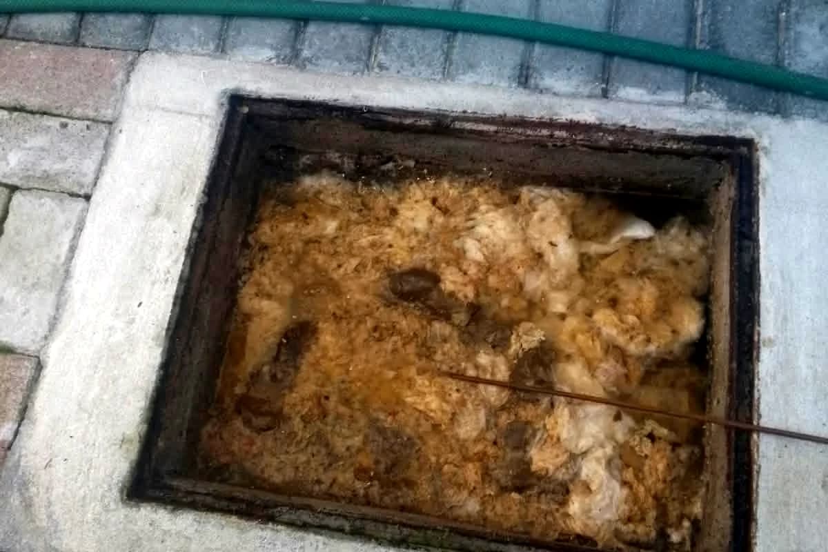 Blocked manhole filled with built-up waste