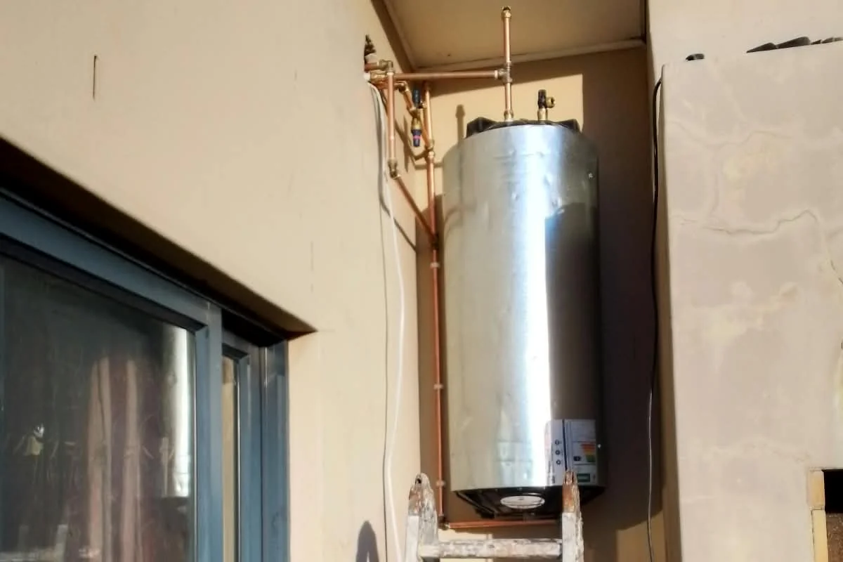 Geyser installed on an outside wall by Sniper Plumbing, with its pipework